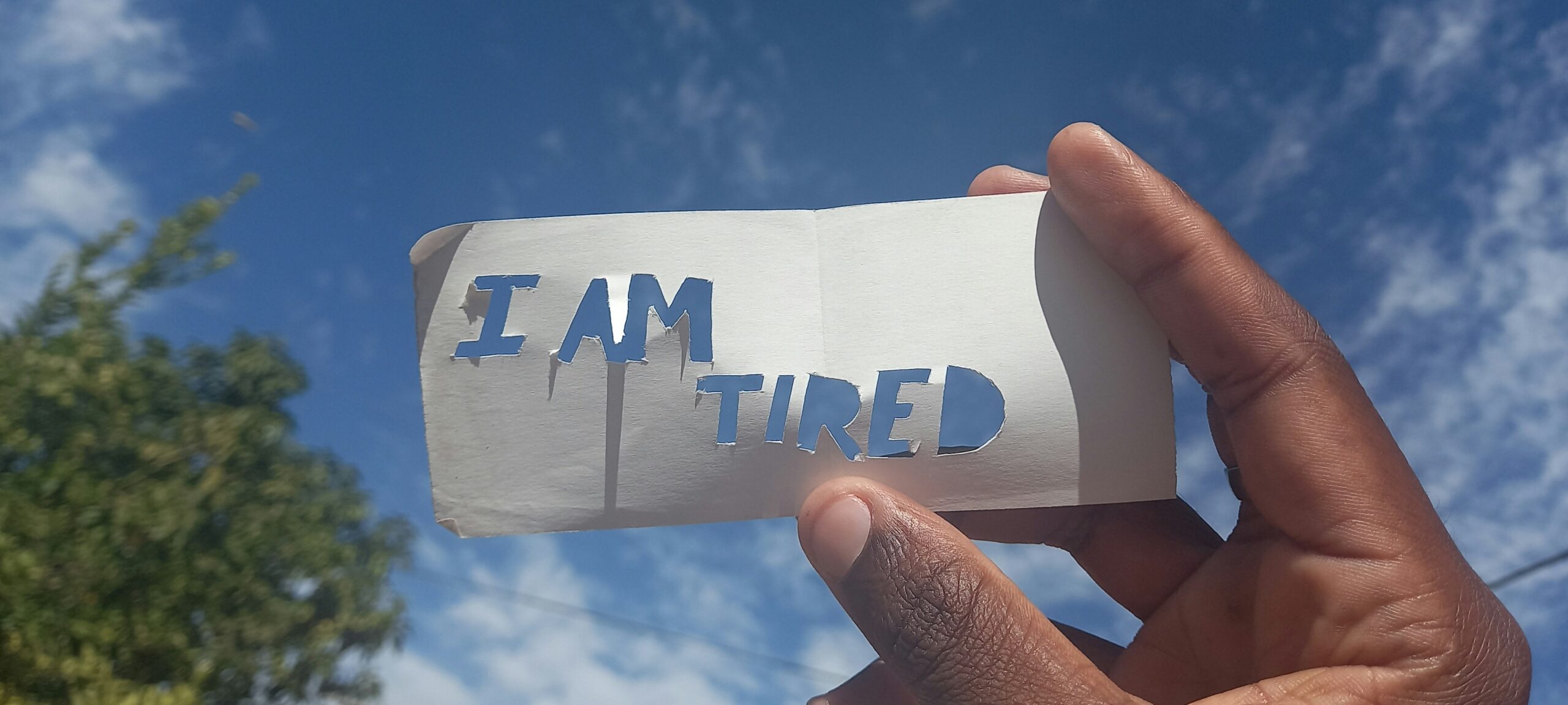 Tangan memegang kertas bertuliskan I Am Tired sebagai ilustrasi relawan yang mengalami compassion fatigue